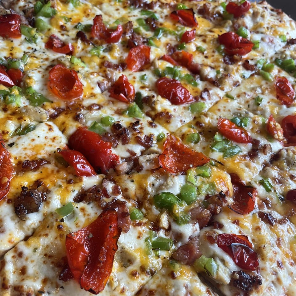 Close-up of a Firehouse Pizza with melted cheese, red peppers, green peppers, and bacon.
