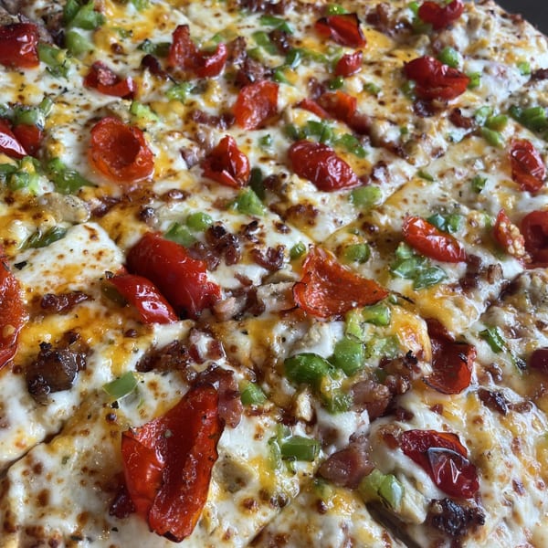 Close-up of a Firehouse Pizza with melted cheese, red peppers, green peppers, and sausage.