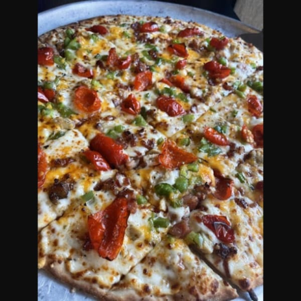 A Firehouse Pizza with melted cheese, red and green peppers, and sausage on a metal pan.