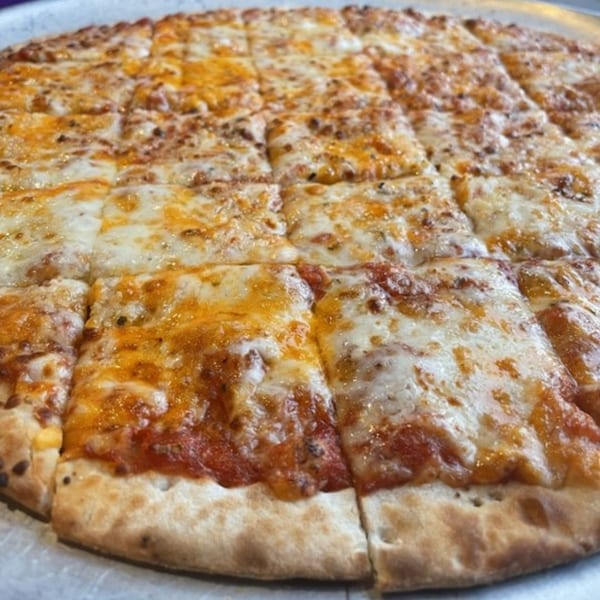 A Firehouse Pizza cheese pizza, cut into squares, with melted mozzarella and cheddar.
