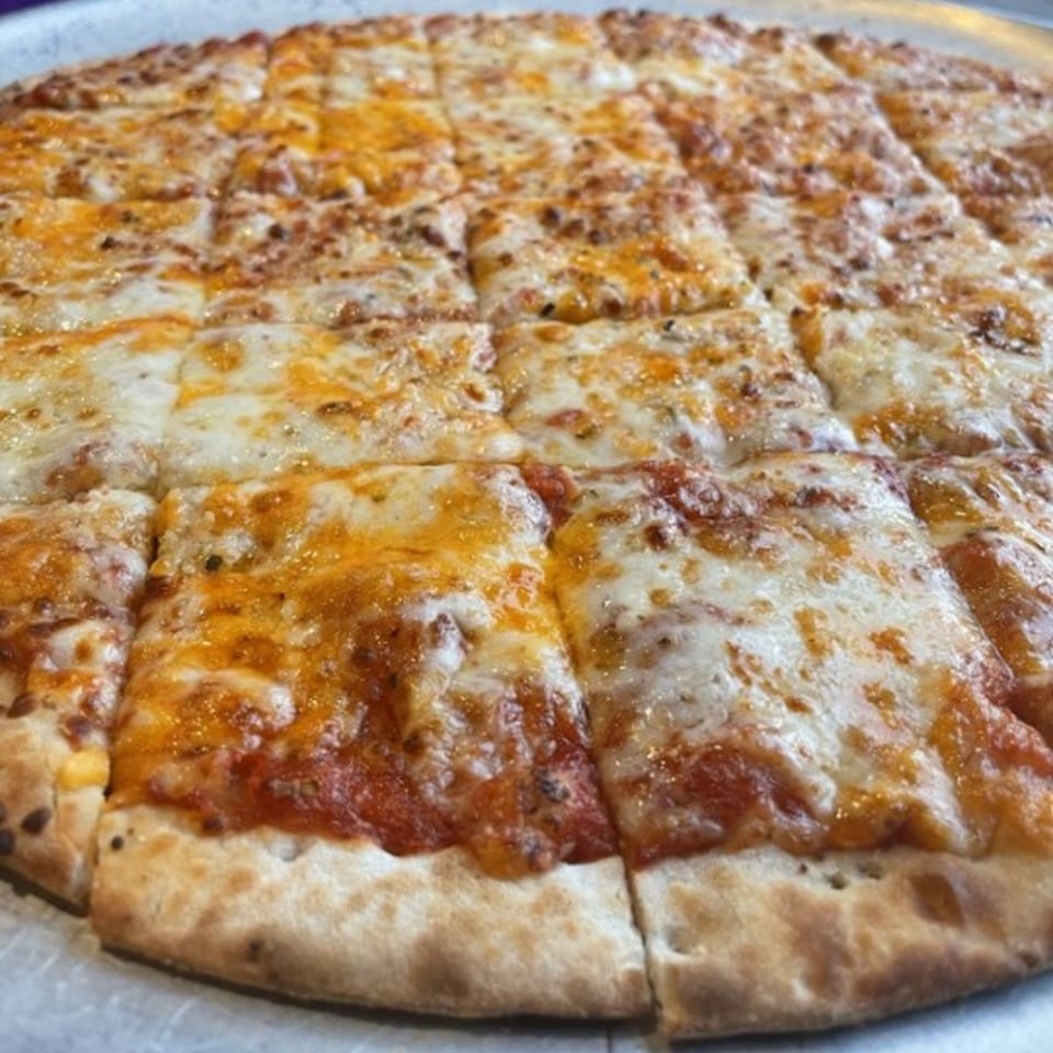 A Firehouse Pizza cheese pizza, cut into squares, with melted mozzarella and cheddar.